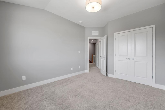 unfurnished bedroom with light colored carpet, baseboards, visible vents, and a closet