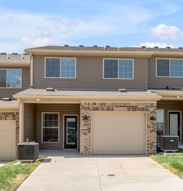 view of property featuring a garage, central AC unit, and driveway