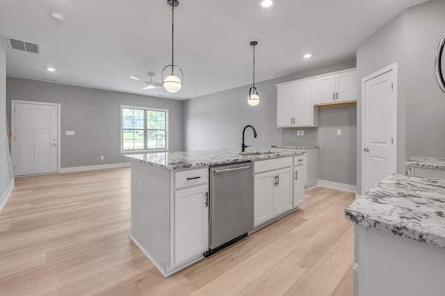 kitchen with stainless steel dishwasher, a center island with sink, white cabinetry, light wood finished floors, and decorative light fixtures