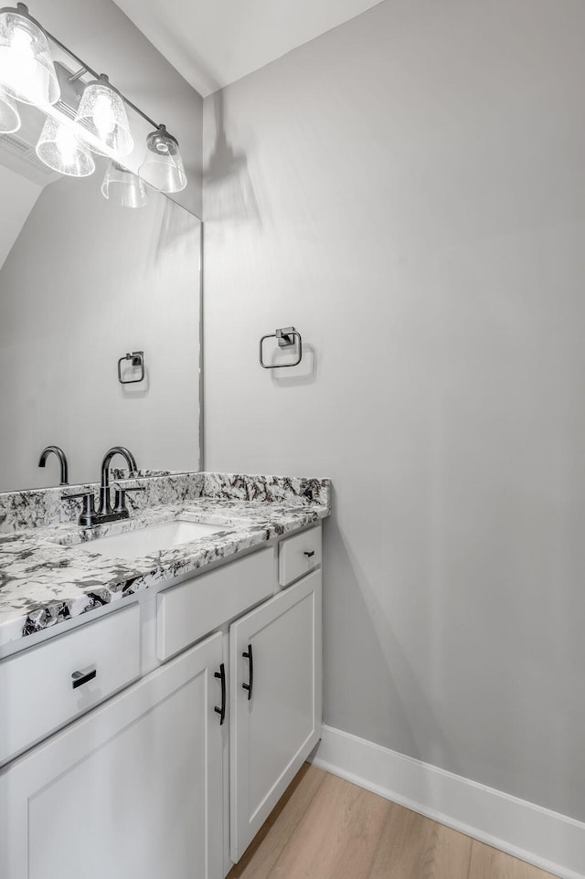 bathroom with baseboards, wood finished floors, and vanity