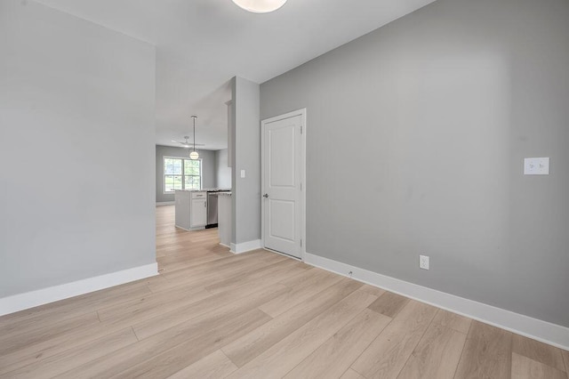 spare room with baseboards and light wood-type flooring