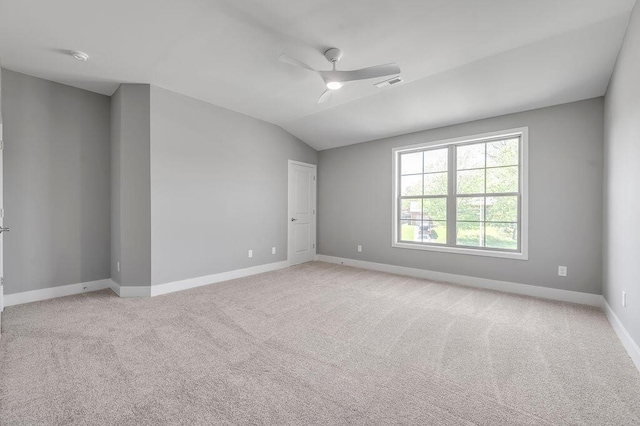 empty room with a ceiling fan, visible vents, vaulted ceiling, baseboards, and light carpet