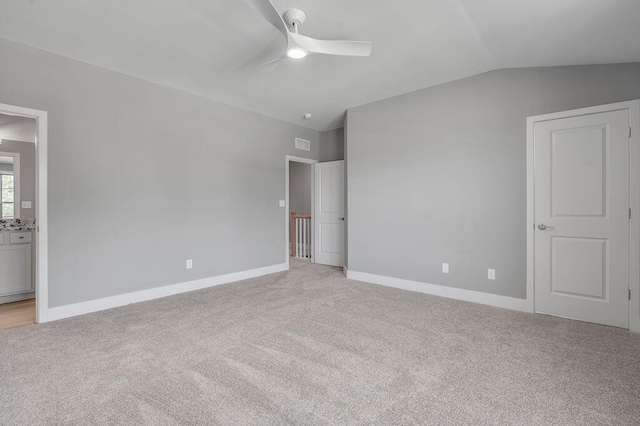 unfurnished bedroom with light colored carpet, baseboards, and vaulted ceiling
