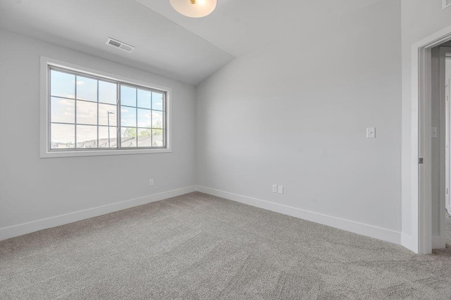 carpeted empty room with visible vents, baseboards, and vaulted ceiling