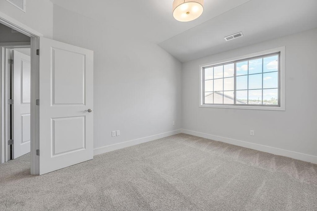unfurnished room featuring visible vents, carpet, lofted ceiling, and baseboards