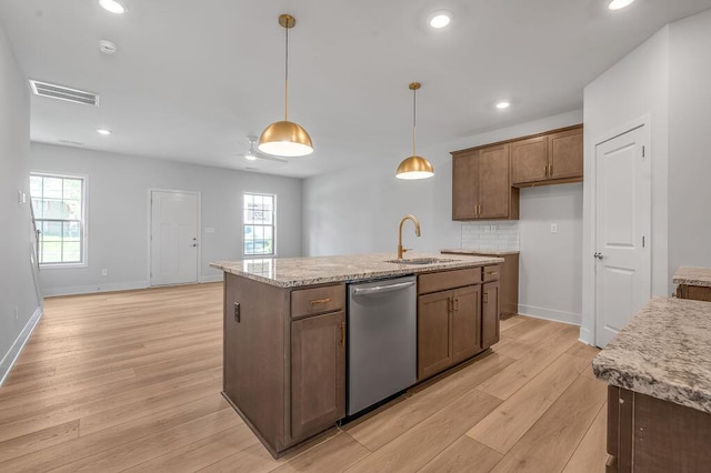 kitchen with a sink, light wood finished floors, dishwasher, an island with sink, and visible vents