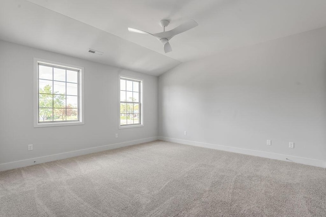 carpeted spare room with a ceiling fan, baseboards, visible vents, and vaulted ceiling