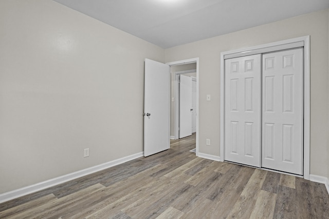 unfurnished bedroom with baseboards, a closet, and wood finished floors