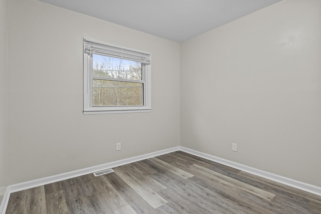 empty room featuring dark wood finished floors, baseboards, and visible vents