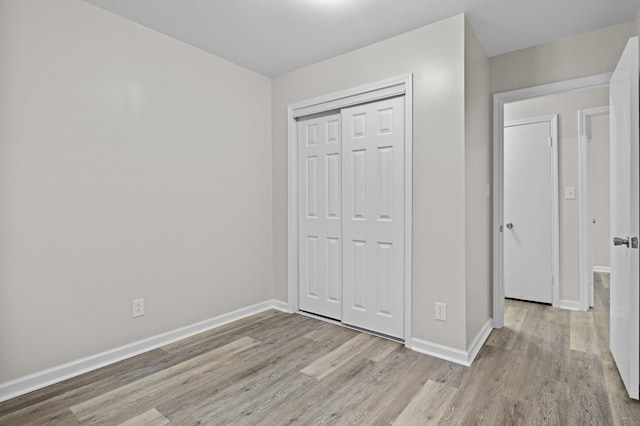 unfurnished bedroom with baseboards, a closet, and wood finished floors
