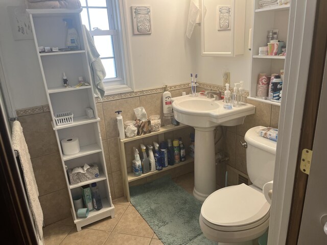 bathroom featuring a wainscoted wall, toilet, tile walls, and tile patterned flooring