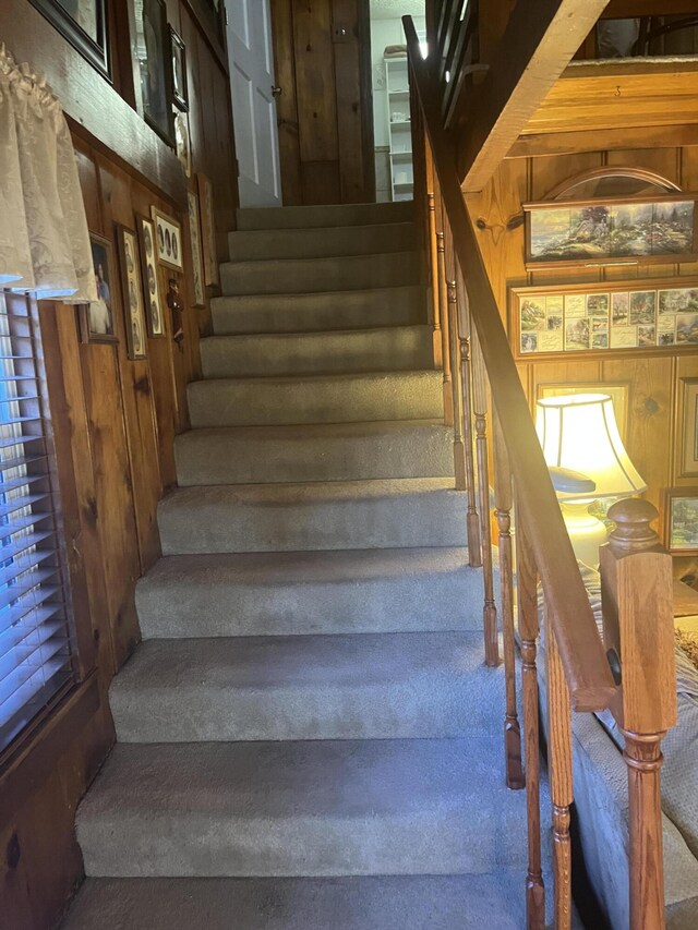 staircase featuring wood walls