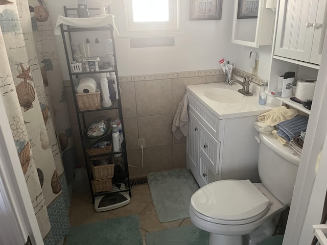 bathroom featuring vanity, tile patterned flooring, wainscoting, tile walls, and toilet