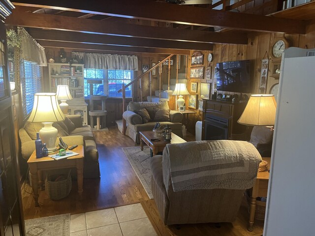 living area featuring stairs, beam ceiling, tile patterned floors, and wood walls
