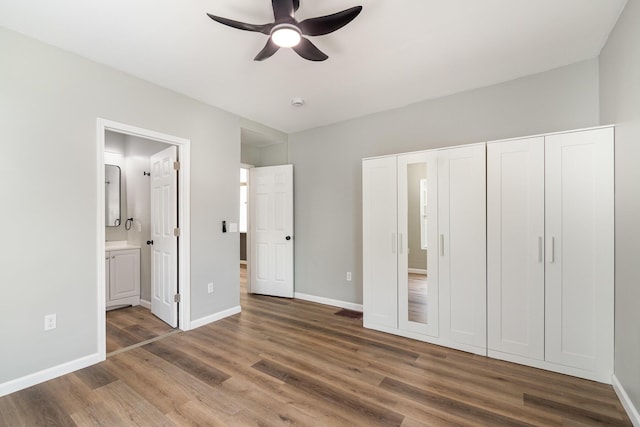 104 W 1st St, Silver Grove, KY 41085 - unfurnished bedroom featuring baseboards, wood finished floors, ceiling fan, and ensuite bath