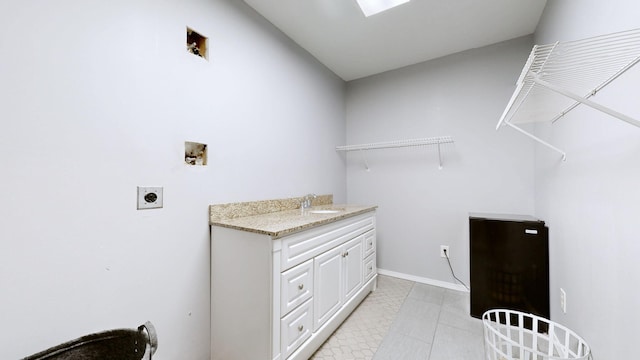 washroom with baseboards, a sink, cabinet space, electric dryer hookup, and washer hookup
