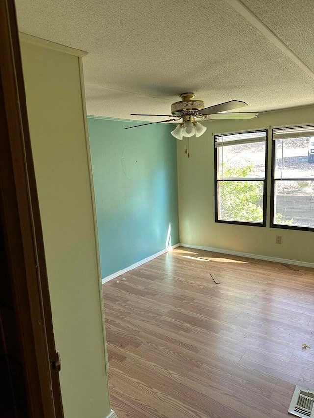 spare room featuring baseboards, a textured ceiling, wood finished floors, and ceiling fan