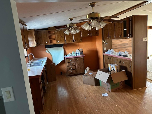 kitchen featuring light countertops, a sink, open shelves, a ceiling fan, and wood finished floors