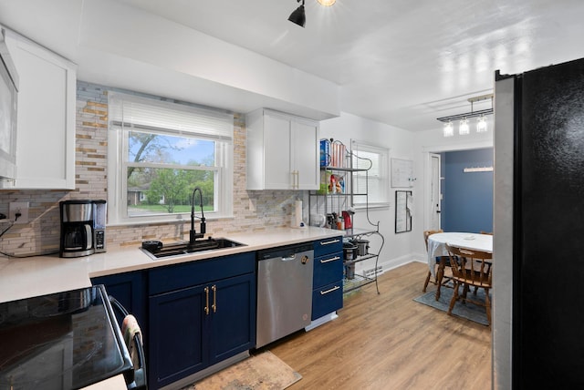kitchen with a sink, decorative backsplash, appliances with stainless steel finishes, and blue cabinets