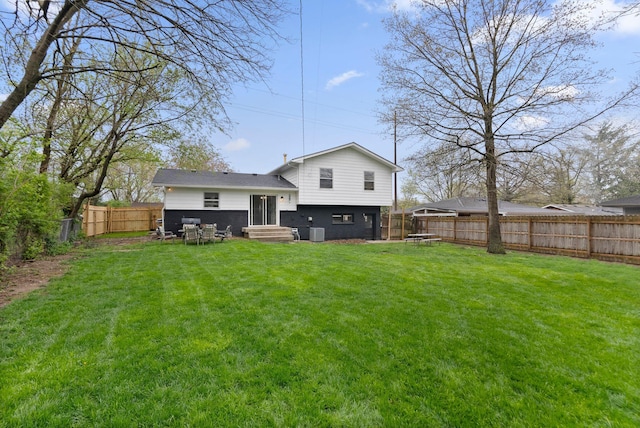 back of house featuring entry steps, a yard, a fenced backyard, and central AC unit