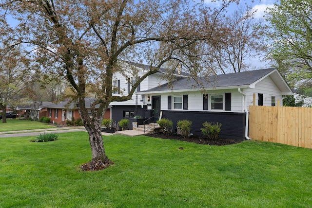 tri-level home with a front yard, fence, and brick siding