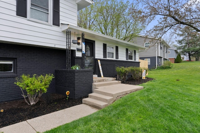 entrance to property with a yard and brick siding