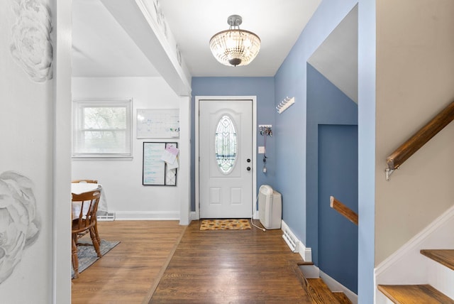 foyer entrance with a notable chandelier, baseboards, and wood finished floors