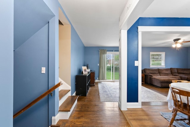 corridor featuring wood finished floors, baseboards, stairway, and a healthy amount of sunlight
