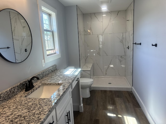 full bathroom with vanity, a marble finish shower, wood finished floors, and toilet