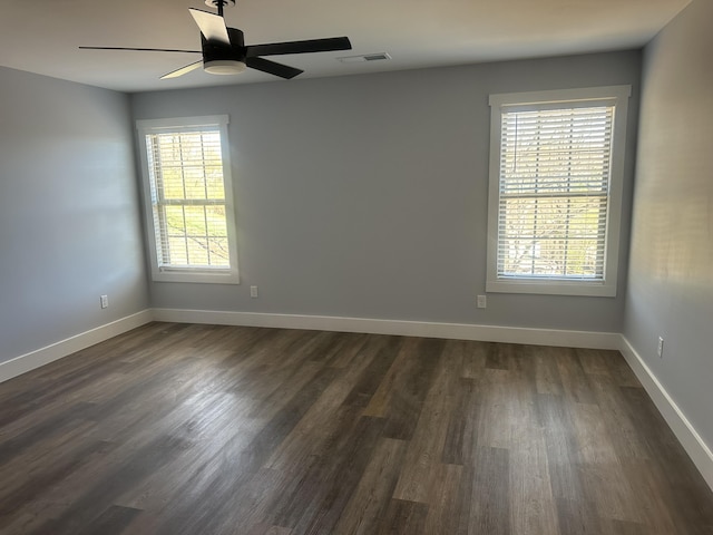 spare room with baseboards, ceiling fan, dark wood-style flooring, and visible vents