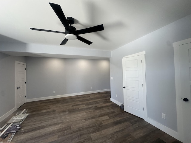 empty room with baseboards, a ceiling fan, and dark wood-style floors