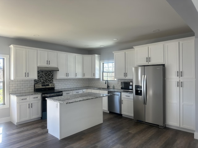 kitchen with decorative backsplash, recessed lighting, under cabinet range hood, white cabinets, and appliances with stainless steel finishes