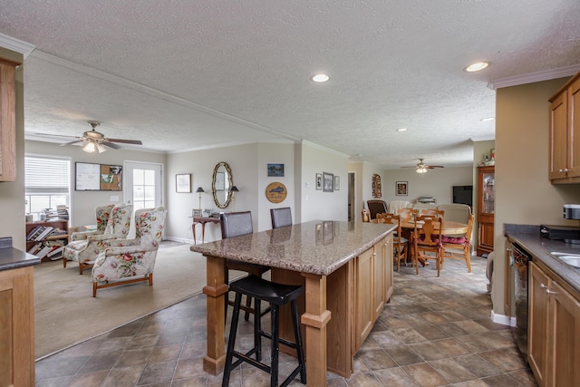kitchen featuring open floor plan, a breakfast bar, ceiling fan, and a kitchen island