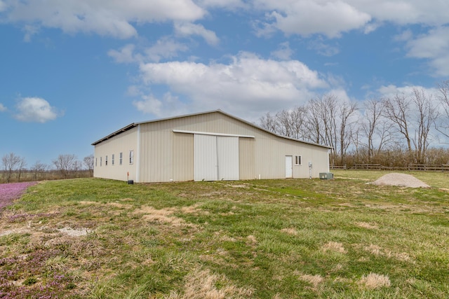 view of pole building featuring central AC, fence, and a lawn