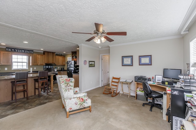 office space featuring a textured ceiling, crown molding, baseboards, a ceiling fan, and light colored carpet