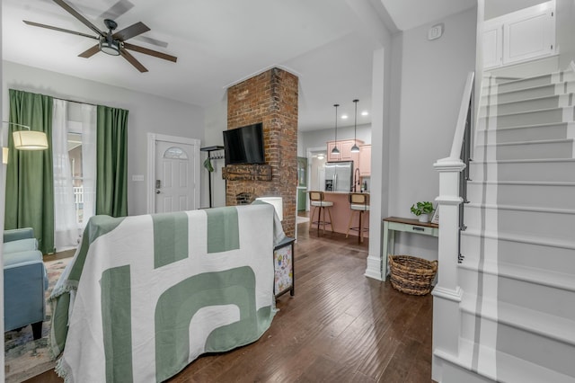living area with a fireplace, a ceiling fan, stairway, baseboards, and dark wood-style floors