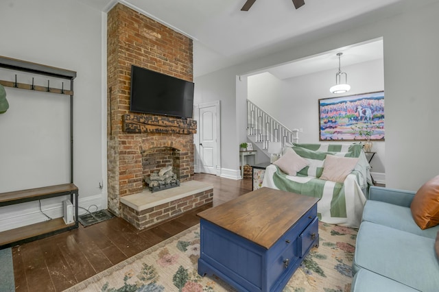 living room featuring baseboards, stairway, a brick fireplace, ceiling fan, and hardwood / wood-style flooring