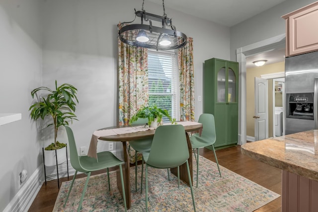 dining space featuring dark wood-style floors and baseboards