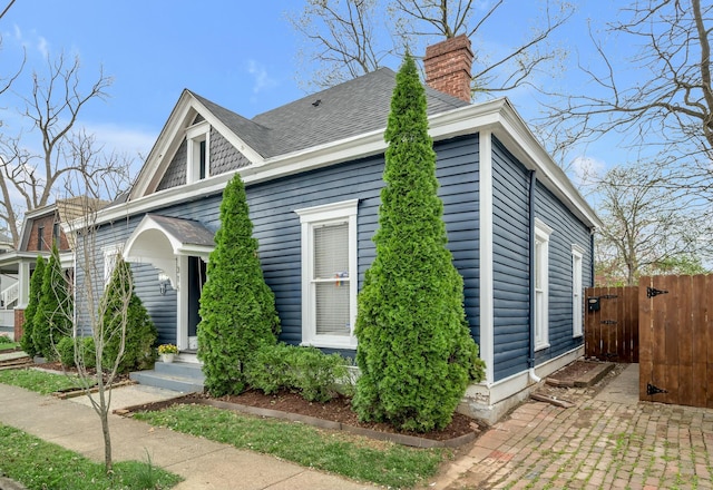 view of side of home featuring a chimney and fence