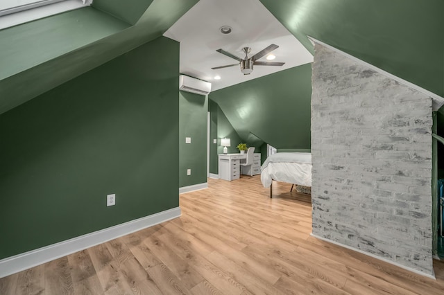 unfurnished bedroom with lofted ceiling, an AC wall unit, baseboards, and wood finished floors