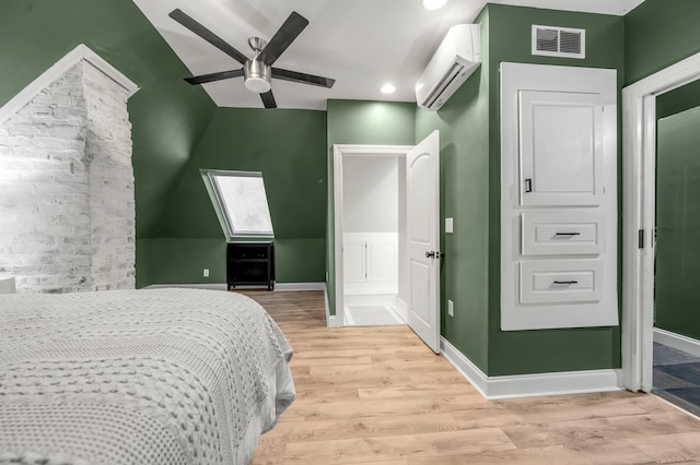 bedroom featuring visible vents, baseboards, a wall mounted AC, light wood-style floors, and vaulted ceiling