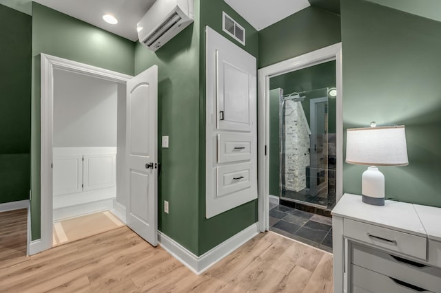 bathroom with a shower stall, visible vents, a wall mounted AC, wood finished floors, and baseboards