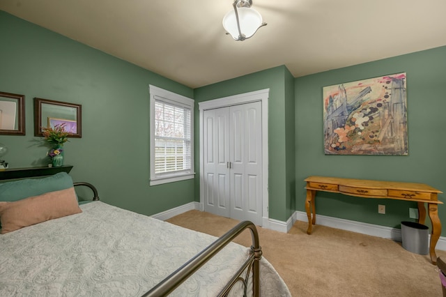 carpeted bedroom with a closet and baseboards