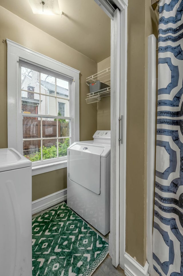 washroom with baseboards and separate washer and dryer