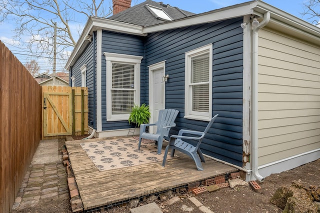 exterior space featuring fence, a deck, a chimney, and a gate