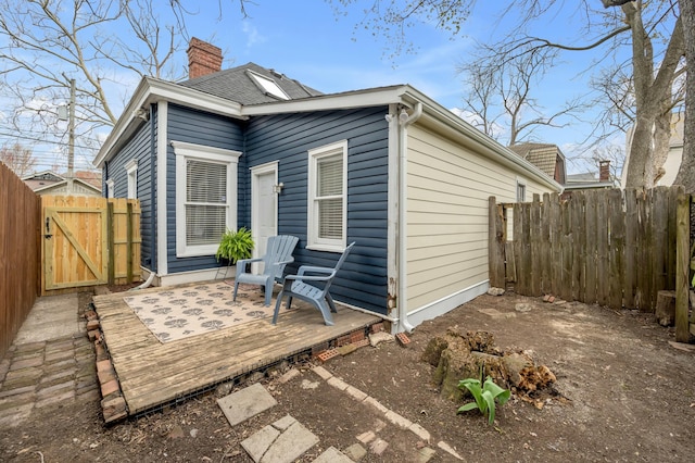 rear view of property featuring fence, a deck, a gate, and a chimney