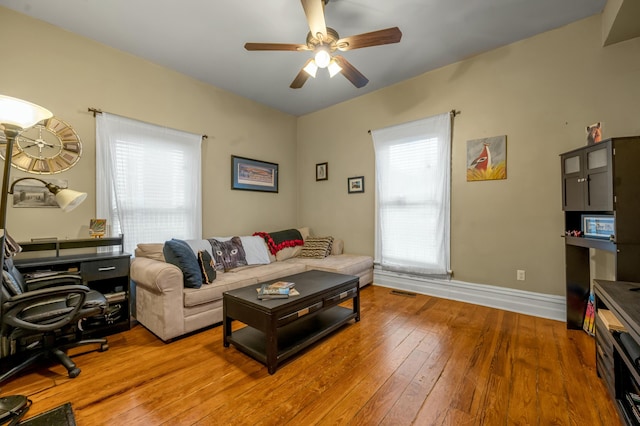 living area with hardwood / wood-style floors, baseboards, and a ceiling fan