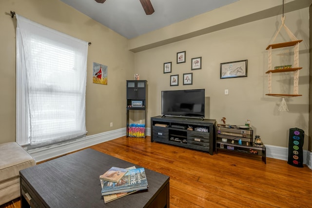 living room featuring wood finished floors, baseboards, and a ceiling fan