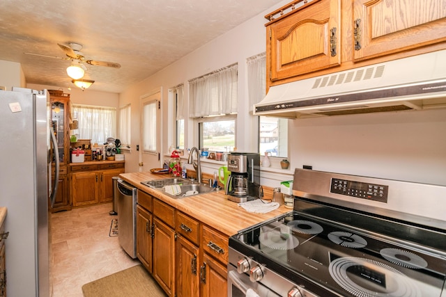 kitchen featuring under cabinet range hood, ceiling fan, a sink, light countertops, and appliances with stainless steel finishes