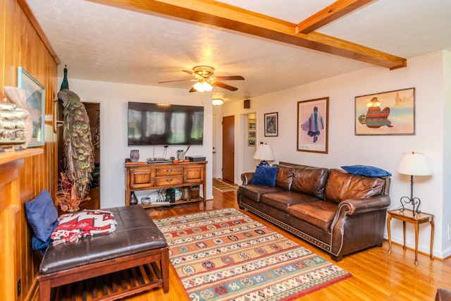 living room with beam ceiling, baseboards, wood finished floors, and a ceiling fan